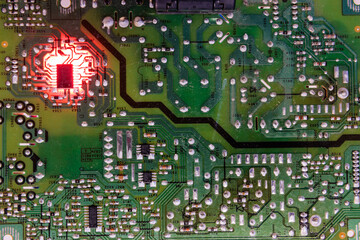 Dusty green circuit board with a glowing red microchip cluster and scattered purple highlights, representing complex electronics, diagnostics and system activity.