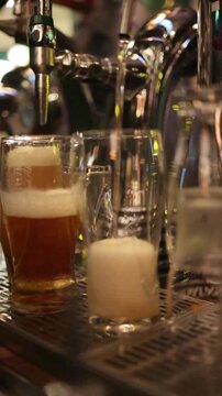 Close-up video of a bartender hand pulling a tap handle as fresh beer or cider flows into a glass, capturing authentic pub atmosphere and professional drink service, 1080p 60fps