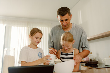 Fototapeta premium Two children and a father joyfully prepare a cake in a modern kitchen. They mix ingredients effortlessly, creating a delightful bonding experience filled with laughter and love.