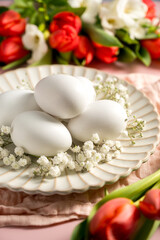 Easter, spring floral background. Red tulips, Fresia and white eggs, flowers on pink background