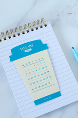 January 2026 calendar on paper coffee cup with notebook. Top view. Monthly planning, business goals, weekly organizer concept.