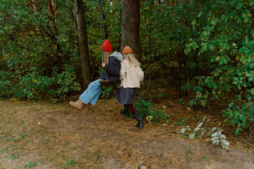 Fototapeta premium Two friends swing joyfully in a serene forest, surrounded by lush green foliage and the warm colors of autumn. Laughter fills the air as they embrace the chilly day with joy.