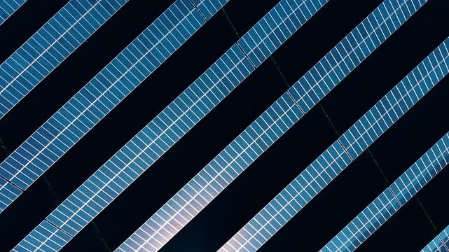 Long rows of solar panels, generating usable power for homes, grids, and devices. Photovoltaic cells absorb sun energy in the fields. Aerial view.