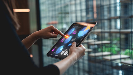 A person interacts with a tablet displaying colorful data visualizations in a modern, stylish environment.
