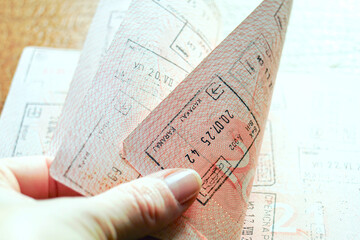 Fingers flipping passport revealing a dense collection of entry stamps. Illustrates travel archive exploration, immigration history browsing, nomadic lifestyle evidence, and wanderlust validation.