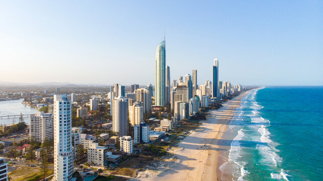 Aerial view of golden sands meet the azure sea alongside towering skyscrapers in Surfers Paradise, Queensland, Australia.