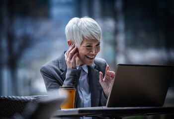 Business woman having video call on laptop in cafe