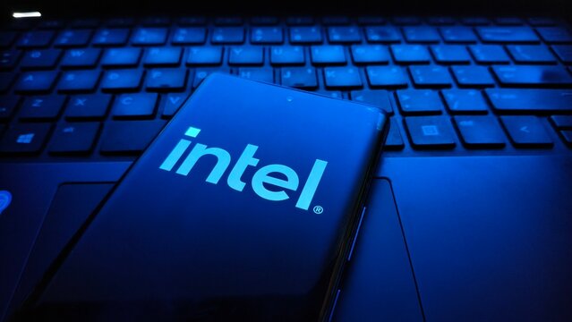 Smartphone displaying the intel logo resting on a dark, backlit laptop keyboard, emphasizing technology and computing  , New York City, 15 December 2025
