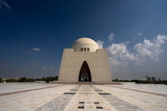 View of the majestic Mazar-e-Quaid mausoleum standing proudly against the azure sky, with its white marble facade and patterned pathway leading to its entrance, Karachi, Sindh, Pakistan.