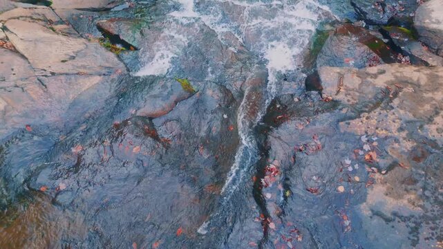 A close-up view of water cascading and flowing over dark, wet rocks, perhaps in a stream or river.