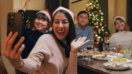 Group of Asia colleague gathering New year holidays party together. Happy friend group mobile phone video call online christmas thanksgiving dinner at home in evening, celebration and people concept.