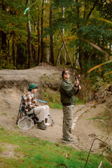Two friends enjoy a peaceful afternoon fishing by a quiet river in the forest. One is casting a line while the other relaxes, surrounded by vibrant trees and nature.
