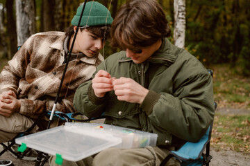Two friends share a moment by the water, focused on fishing together. Surrounded by trees, they...