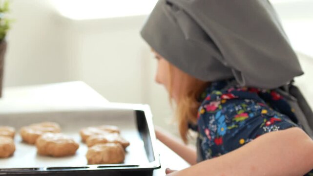 Little girl baker holding in hands baking sheet with homemade cookies