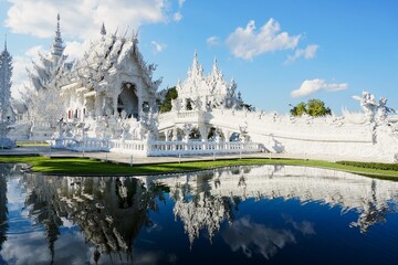 Detailed exterior view of the ornate white plasterwork and glass mosaics of Wat Rong Khun temple, showcasing traditional Thai motifs with a modern artistic twist.