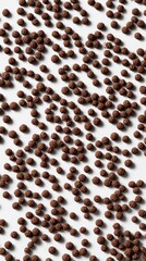 A whimsical arrangement of brigadeiro sprinkles covers a smooth white surface, showcasing their rich brown color and tiny, round shapes. These sweet decorations invite creativity in dessert crafting