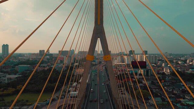 symmetric modern cable-stayed Rama VIII bridge over Chao Phraya river in Bangkok, perspective of contemporary suspension urban span connecting city skyline across Thai waterway, aerial drone view 4k