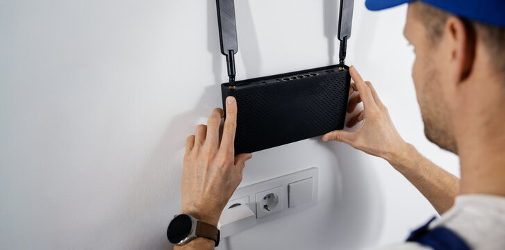 Wireless internet. Service technician installing Wi-Fi router on interior wall at home. copy space