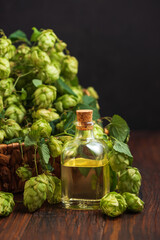 Hop Extract in Glass Bottle with Fresh Hops on Wooden Surface