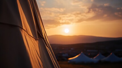 Canvas tent at golden sunset with warm glow over mountain range