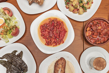 Asturian fabada steaming in its pot, accompanied by an assortment of cured meats and roasted peppers with their dark skin and sweet flesh.