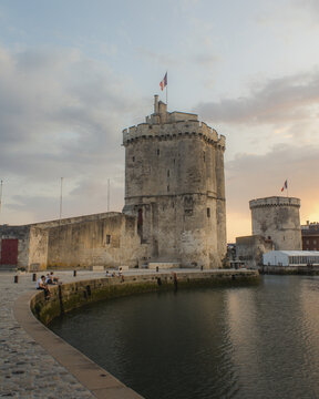 View of the imposing medieval towers of La Rochelle stand as silent sentinels against the pastel-streaked sky, La Rochelle, Nouvelle-Aquitaine, France.