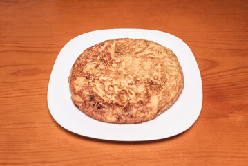 Individual plate with a pincho of potato omelet, a square piece held together with a toothpick, as traditionally served in Spanish bars