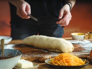 Hands skillfully prepare to slice a golden dough log filled with walnut and cocoa. The essence of Balkan culture shines in this festive sweet bread, perfect for holiday gatherings