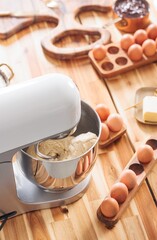 A cozy kitchen scene features a mixer preparing dough for Kozonac, surrounded by eggs, cocoa, and butter. The rich aroma of tradition fills the air as the festive bread is created