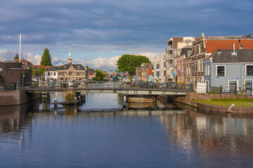 View of calm waters reflecting the bridge and buildings under a dramatic sky, creating a serene atmosphere in Leiden, South Holland, Netherlands.