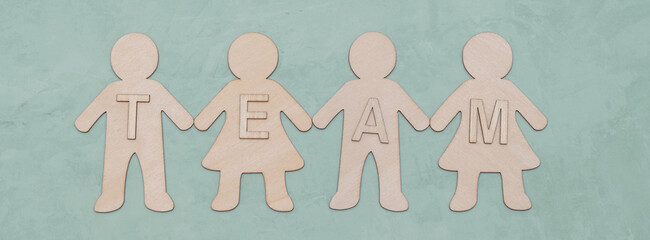 Team concept with cut-out wooden figures and blocks that represent the word 