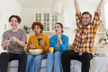 Home party. Cheerful group of friends playing video games at home. Happy diverse group buddies having fun together indoor. Friendship leisure entertainment concept. Young best friends enjoying weekend