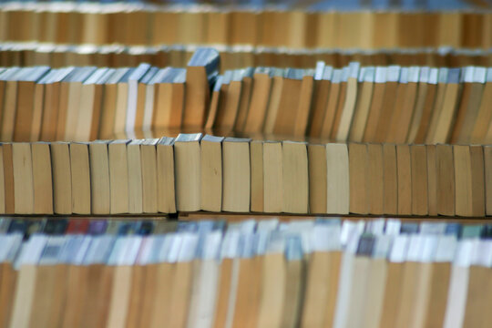 Book Market. Rows of vintage books on shelves. A large collection of old paperback books arranged neatly with a shallow depth of field.