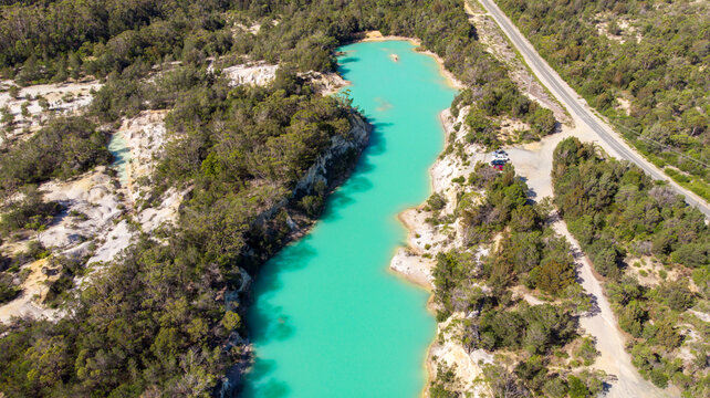 Aerial view of the startling turquoise waters of Little Blue Lake contrast sharply with the surrounding ochre earth and dense green forest, Little Blue Lake, Tasmania, Australia.