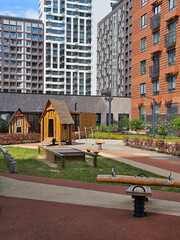 Playground with a swing set and a small house. The playground is in front of a large building