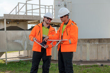 Engineers comparing solar panel reading with data sheet at turbine base on wind farm reviewing renewable maintenance task supporting clean energy workflow for sustainable power technology application
