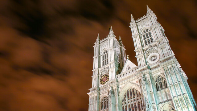 Westminster Abbey towers at night. The historic Gothic towers of Westminster Abbey illuminated against a moving cloudy night sky.