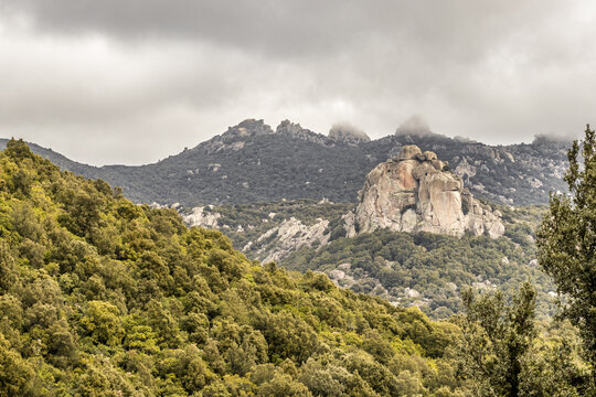 View of the granite peaks and lush green forests, with clouds touching the mountain tops, Parco dei Sette Fratelli, Sardinia, Italy.