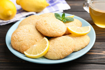 Tasty lemon cookies and fruit slices on black wooden table, closeup