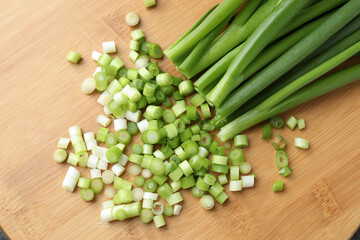 Cut fresh green onions on wooden board, top view