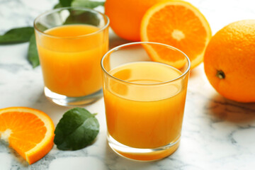Fresh orange juice and fruits on white marble table, closeup