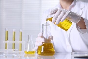 Scientist checking motor oil quality at table in laboratory, closeup. Space for text