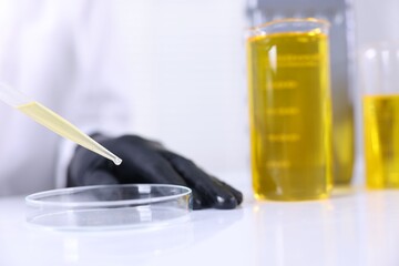 Scientist checking motor oil quality at table in laboratory, closeup