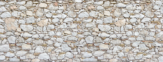 Irregularly shaped light stones composing an old wall surface