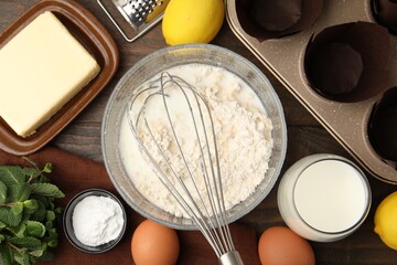 Ingredients for making muffins and cupcake tray on wooden table, flat lay