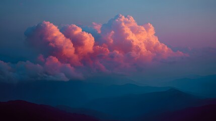 Towering cumulus clouds illuminated with vivid pink and orange light above layered blue mountain ridges at twilight