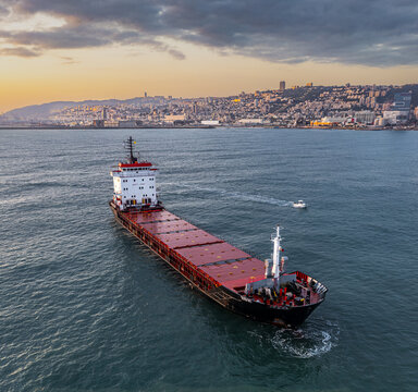 Aerial view of a bulk carrier ship sailing near the cityscape with the Bahai Gardens visible in the background, Haifa, Israel.