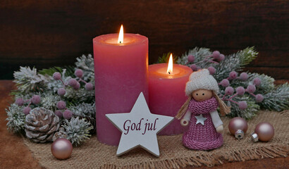 Christmas card: Pink candles with Christmas decorations and a small doll on a star bears the...