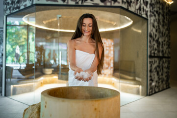 Excited young woman in a towel preparing for the spa salt therapy in spa center