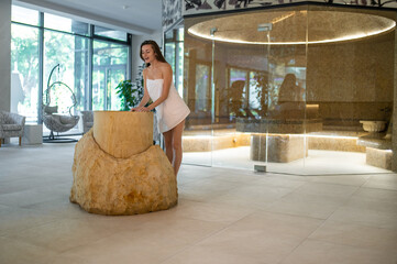 Excited young woman in a towel preparing for the spa salt therapy in spa center